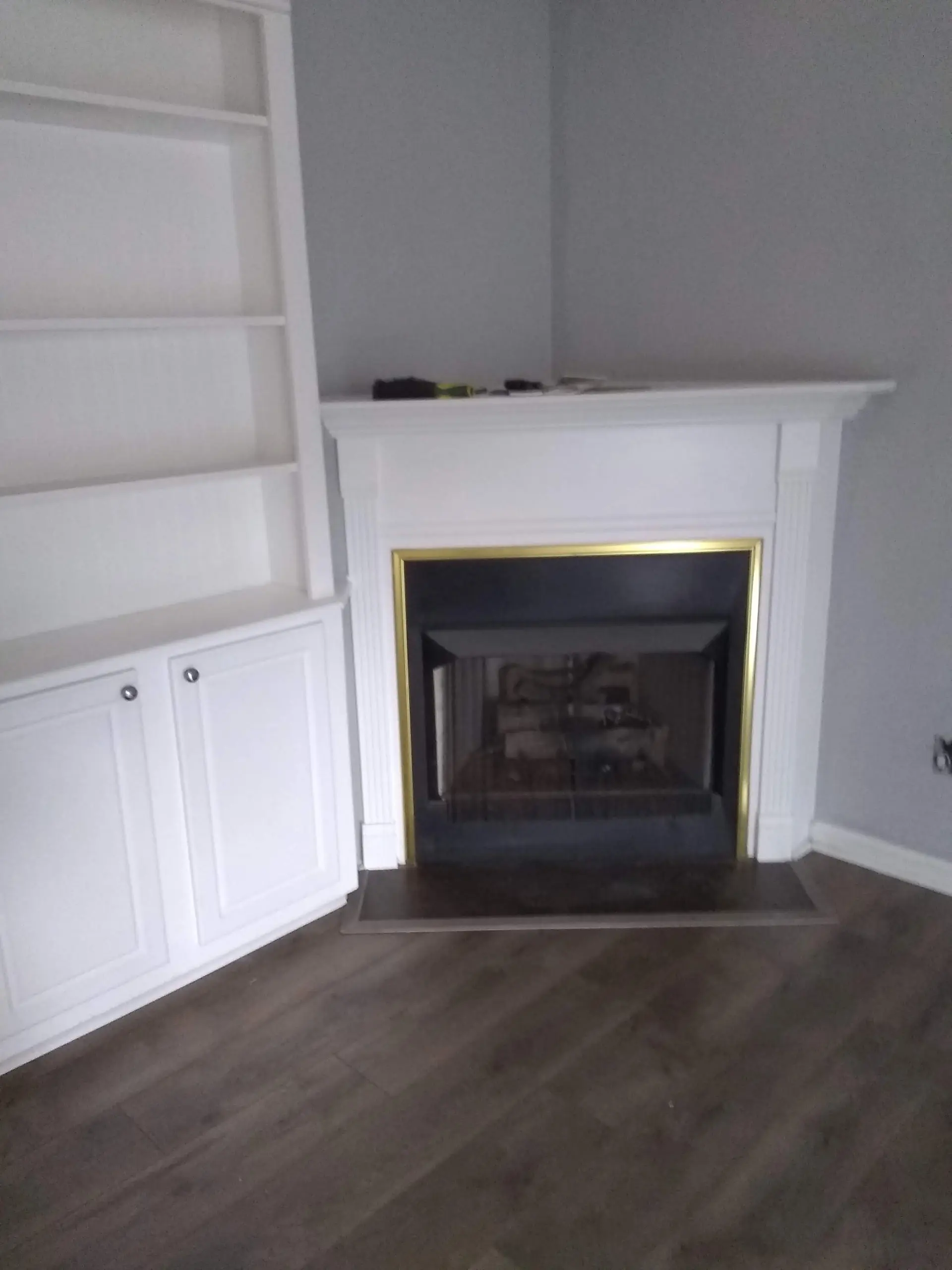 Gray vinyl plank flooring beside a white fireplace with built-ins