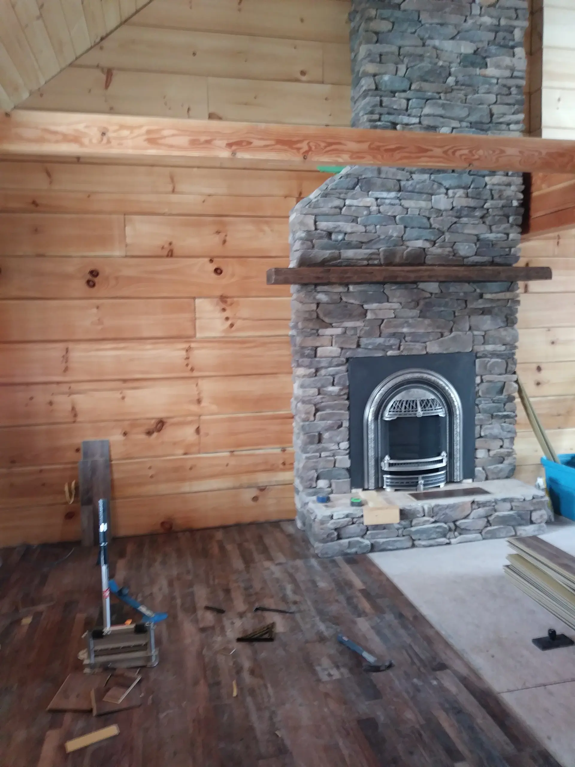 Rustic plank flooring in a log cabin with a stacked stone fireplace
