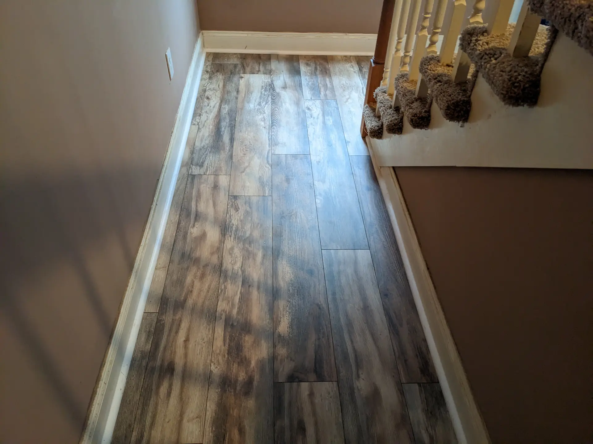 Rustic multi-tone plank flooring on a staircase landing hallway